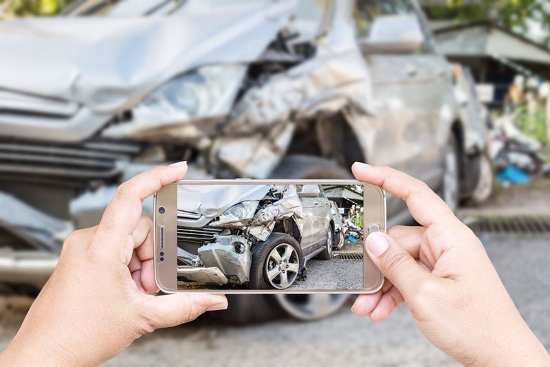person taking photos of a car accident with their mobile phone